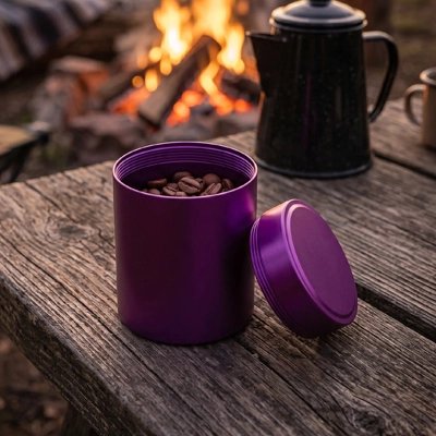 Boite a café rempli de café en grain sur table en camping