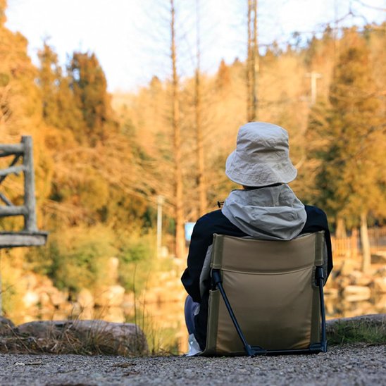 Chaise de camping avec une personne qui pêche sur le bord de l'eau