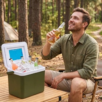 Glacière sur table au camping et un homme qui boit