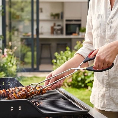 Pince barbecue​ homme retirant les brochettes qui son prêt