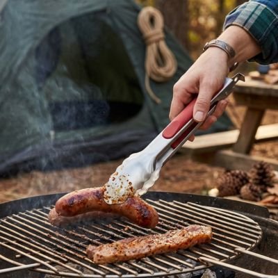 Pince barbecue personne qui retourne viande sur barbecue